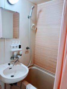 La salle de bains est pourvue d'un lavabo et d'une douche. dans l'établissement Luxes Hiroshima2F ラクセス ヒロシマ2F, à Hiroshima