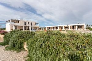 ein Haus am Strand mit Busch davor in der Unterkunft Agriturismo "Lu Puzzu" in Torre Lapillo