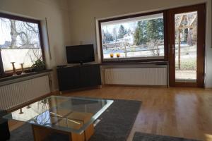 uma sala de estar com uma mesa de vidro e 2 janelas grandes em Haus Eifeldolomiten - Ankommen und Wohlfühlen em Gerolstein