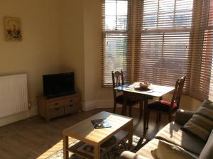 a living room with a table and a tv at One bedroom flat on a quiet road in Colwyn Bay