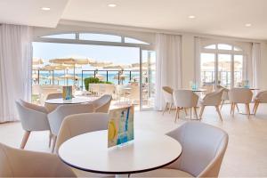 een restaurant met tafels en stoelen en uitzicht op de oceaan bij Grupotel Dunamar in Can Picafort