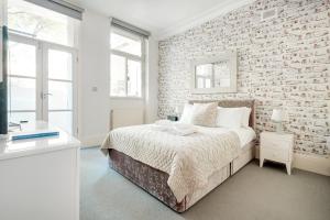 um quarto branco com uma parede de tijolos e uma cama em Stunning Home near Earl's Court by UndertheDoormat em Londres