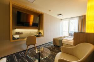 a hotel room with a bed and a chair and a tv at Hotel Hills in Tatranská Lomnica