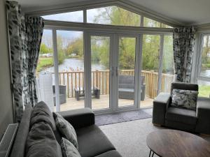 uma sala de estar com um sofá e uma porta de vidro em Beautiful and Tranquil Lakeside Lodge - Sleeps 5 em Northampton