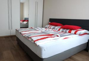 a bed with red pillows on it in a bedroom at CAMPANELL - Das Ferienhaus im Blaufränkischland in Deutschkreutz