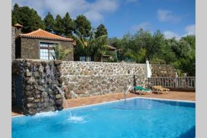 a swimming pool in front of a stone wall at CASAS COREA in Puntagorda