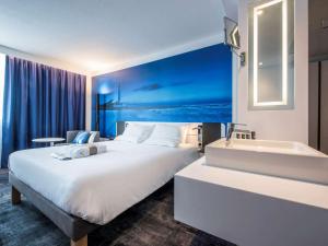 um quarto de hotel com uma cama grande e uma banheira em Novotel Rennes Alma em Rennes