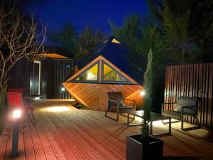 ein winziges Haus mit einer Holzterrasse in der Nacht in der Unterkunft LA RÉSERVE DE L'AUBE - Hébergements insolites Luxe et Design in Villenauxe-la-Grande