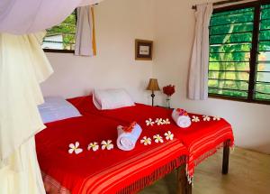 a bedroom with a red bed with flowers on it at A Rocha Eco-Lodge & Conservation Centre in Watamu