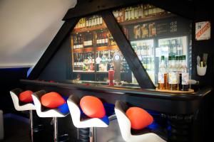un bar con sgabelli bianchi e arancioni in una stanza di Le Loft de Zoé a Saint-Sylvain