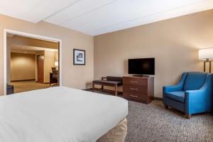 a hotel room with a bed and a tv and a chair at Comfort Suites Downtown Carlisle in Carlisle