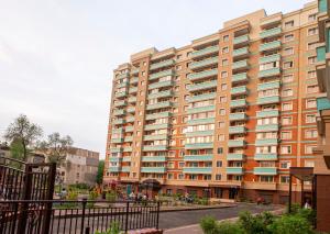 un gran edificio de apartamentos con una calle enfrente en Уютная студия с видом на горы en Almaty