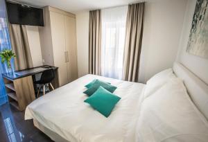 Un dormitorio con una cama blanca con almohadas verdes. en Self Service Hotel Kernhof Langstrasse, en Zúrich