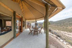 un porche de una casa con mesa y sillas en Grysbokkloof Private Nature reserve luxury Glamping 6km from Montagu en Montagu