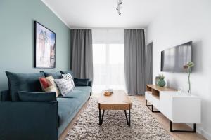 a living room with a blue couch and a table at Apartments Steam Park Old Town Cracow by Renters in Krakow