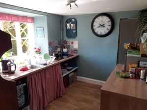 a kitchen with a counter and a clock on the wall at Beautiful Devon Farmhouse in Exeter