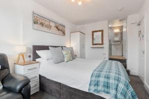 a bedroom with a large bed and a chair at Coach Guest House in Tenby
