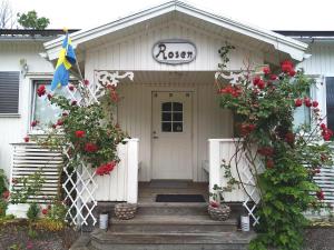 Uma casa branca com flores vermelhas à frente. em Skotteksgården Cottages em Ulricehamn