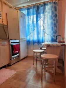 マグニトゴルスクにあるApartment on Domenshchikovのキッチン(カウンター、スツール2つ、冷蔵庫付)