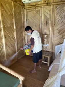 a man standing in a yurt playing with a hose at Elang Hillside Bamboo Villas in Labuan Bajo