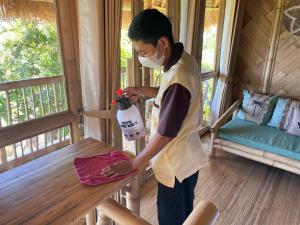 a man wearing a mask holding a bottle on a porch at Elang Hillside Bamboo Villas in Labuan Bajo