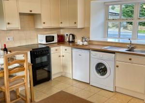 a kitchen with a washing machine and a microwave at Church House Farm in Danby