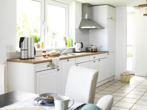 a kitchen with white cabinets and a table at 12 persoons accommodatie in Loosdrecht