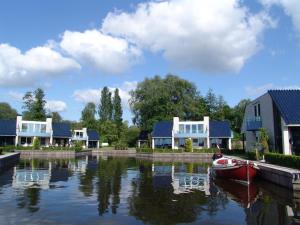 a boat in the water in front of some houses at 12 persoons accommodatie in Loosdrecht