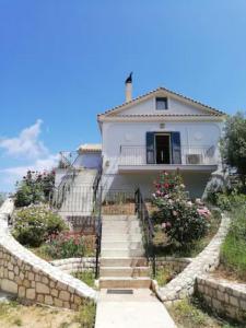 a white house with stairs leading up to it at OliveTree House in Vathi