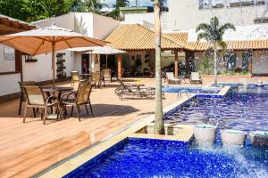 a pool with a table and chairs and an umbrella at Hotel Chapadao Da Canastra in São Roque de Minas