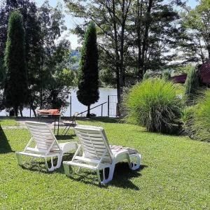 2 chaises blanches assises sur l'herbe dans une cour dans l'établissement Vikendica DRINSKI DAR, à Mali Zvornik