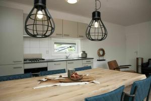 a kitchen with a wooden table with blue chairs and lights at 6 6 persoons Veluwe Villa met sauna en grillhuis in Voorthuizen