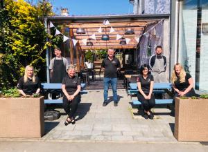 a group of people sitting on benches in front of a building at The Drymen Inn in Drymen