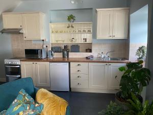 a kitchen with white cabinets and a sink at Ellers Farm Cottage in Carnforth