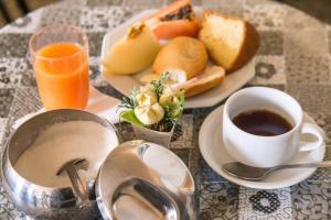 a table with a plate of food and a cup of coffee at Pousada Rio Branco Nova Lima - By UP Hotel in Nova Lima