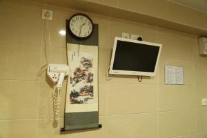 a clock on a wall with a phone and a monitor at Narli Guest House in Hong Kong