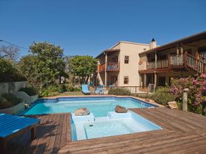 una piscina con terrazza in legno accanto a un edificio di At the Woods Guest House a Stormsrivier