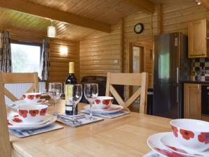 a dining room table with glasses and a bottle of wine at Viaduct Fishery Holiday Lodges in Somerton