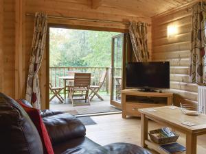 a living room with a television and a screened in porch at Viaduct Fishery Holiday Lodges in Somerton