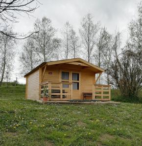 una pequeña casa de madera en un campo con árboles en Schlaffass und Hütte mit Teich, en Klöch