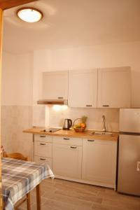 una cocina con armarios blancos y fregadero en Mljet Sunset Apartments en Pomena