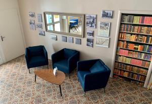 パラヴァ・レ・フロにあるHotel Le Petit Baigneur Palavas Plageの椅子2脚、テーブル、本が備わる待合室