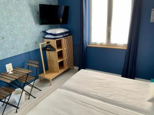 a bedroom with a bed and a tv and a chair at Hôtel Le Petit Baigneur in Palavas-les-Flots