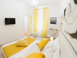 a white bedroom with a large bed with yellow pillows at Maison San Paolo in Sorrento