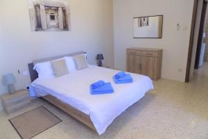 een slaapkamer met een groot bed met blauwe handdoeken bij Sunshine Holiday Apartment 5 with Spectacular Seaviews in St Paul's Bay