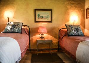 a room with two beds and a table with two lamps at Aguapé Lodge in Colonia Carlos Pellegrini