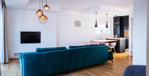 a living room with a blue couch and a kitchen at Apartman Eden in Rožnov pod Radhoštěm