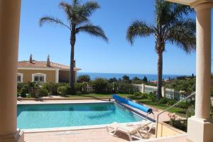 een zwembad met palmbomen en een huis bij Vila G, Mira Luz in Luz