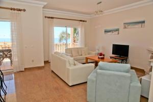 een woonkamer met twee witte stoelen en een televisie bij Vila G, Mira Luz in Luz