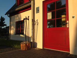 una puerta roja de un edificio con un tronco de árbol al lado en Zur Bergwiese 5 Sterne Appartementhaus, en Fürstenau